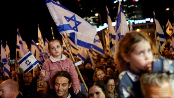 People hold Israeli flags during a protest against Israel's Prime Minister Benjamin Netanyahu's new right-wing coalition and its proposed judicial changes to reduce powers of the Supreme Court in Tel Aviv, Israel February 18, 2023. REUTERS/Amir Cohen