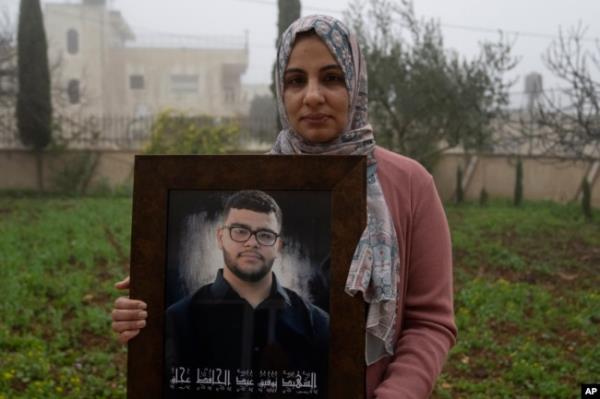 Mona, 36, mother of Tawfic Abdel Jabbar, poses with a f<em></em>ramed photo of her son at the family's Palestinian home in the West Bank on Jan. 23.