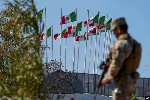 Within sight of flags flying in Mexico, a guardsman keeps watch along the Rio Grande in Eagle Pass, Texas, Jan. 3, 2024.