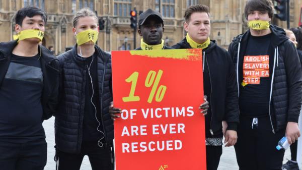 People marching against modern slavery through Lo<em></em>ndon wearing face masks representing the silence of modern slaves in forced labour and sexual exploitation