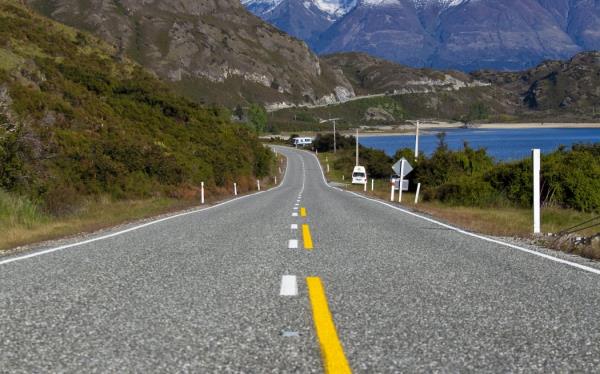 An empty stretch of road in New Zealand's South Island, with mountains and a lake in the background