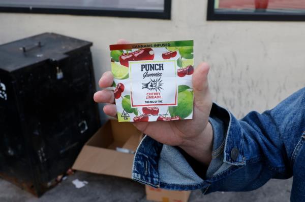 A man's hand holding a bag of marijuana candies that says 