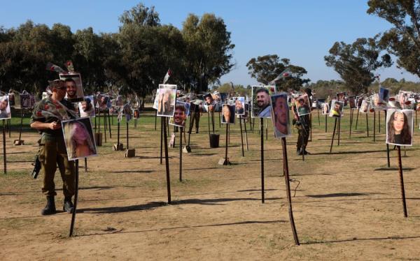 Israeli soldiers walk on 30 November 2023 among the pictures of people taken captive or killed by Hamas militants duing the Supernova music festival on 7 October, at the site wher<em></em>e the deadly incident took place near Kibbutz Reim in southern Israel.