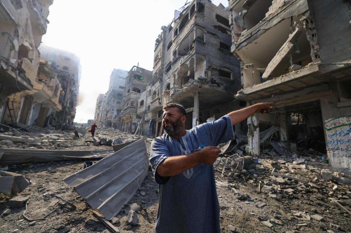 A Palestinian man points at destruction as people inspect the damage following overnight Israeli airstrikes in the Gaza Strip's Jabalia refugee camp, Oct. 11, 2023. (AFP Photo)