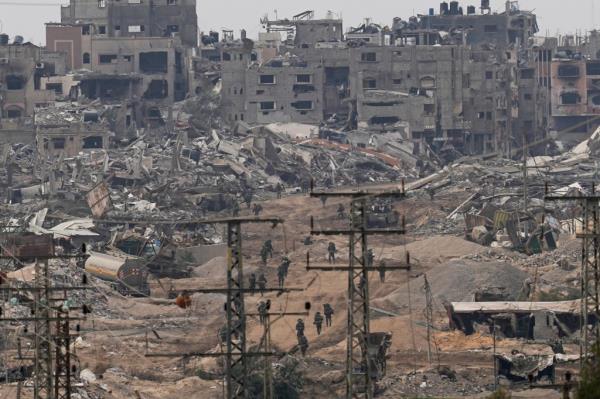 Israeli troops walk in the Gaza Strip as seen from southern Israel, Thursday, Dec. 21, 2023. The army is battling Palestinian militants across Gaza in the war ignited by Hamas' Oct. 7 attack into Israel. (AP Photo/Ohad Zwigenberg)