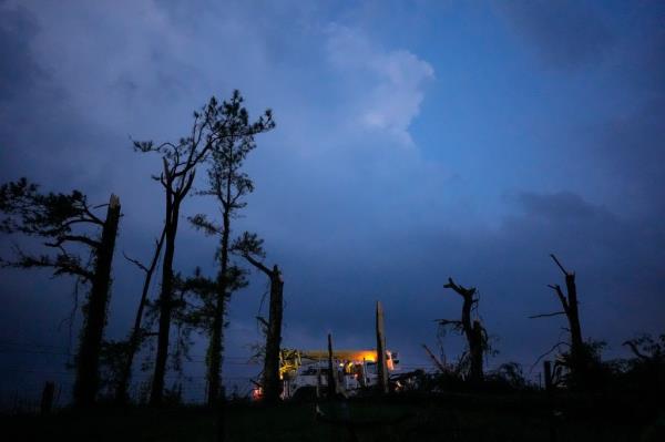 A utility truck passing by storm-damaged trees along a road in Columbia, Tennessee