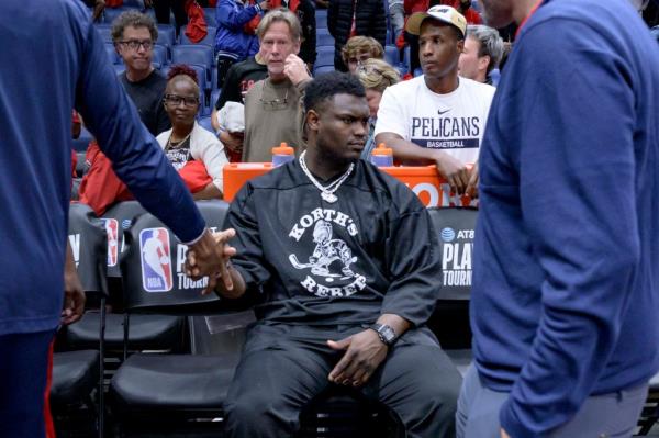 Pelicans forward Zion Williamson sits on the bench as teammates pass by after the Pelicans lost