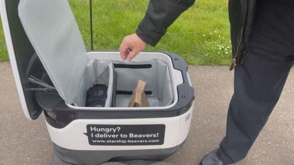 A person takes their food out of the robot.