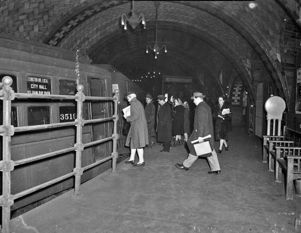 Passengers are seen boarding a train at Old City Hall during its original use in a black and white picture.