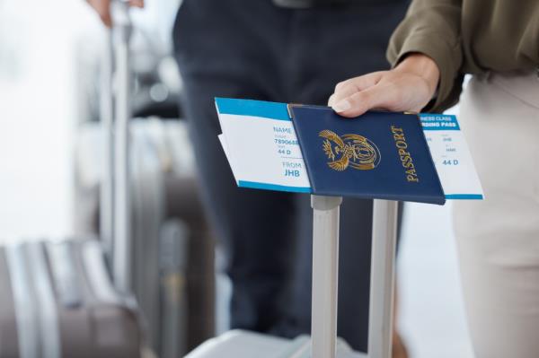 Hand of a passenger holding passport and ticket