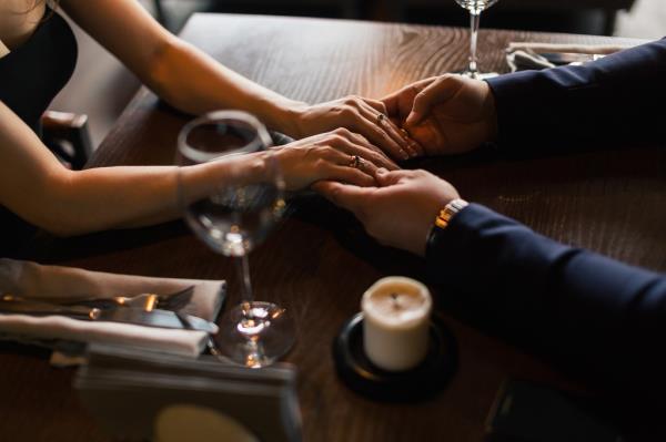 Couple holds hands over a dinner table