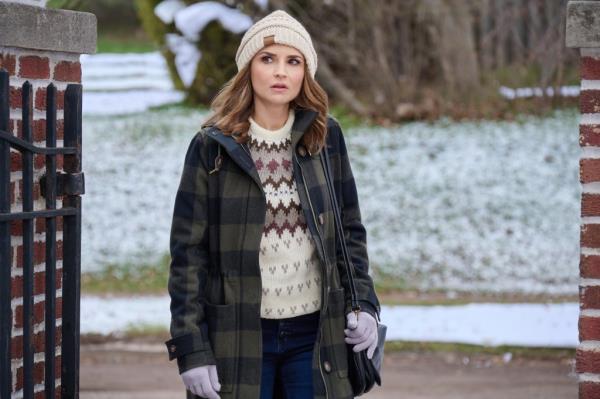 Rachael Leigh Cook in a hat standing outside. 