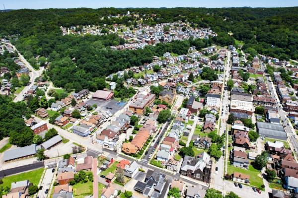 Aerial view of a residential neighborhood surrounded by lush green vegetation in Pittsburgh, Pennsylvania.