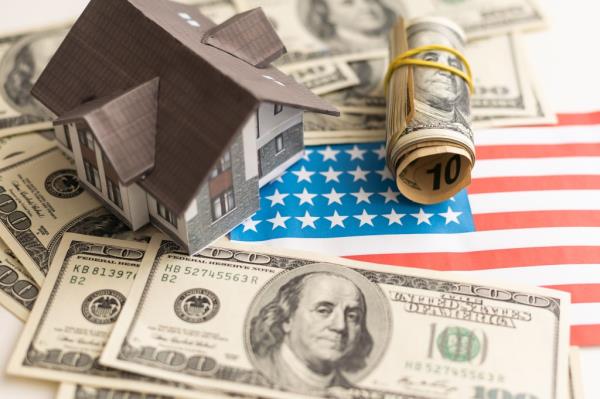 A toy house made of wood with a roof costs money, on a hundred-dollar bill