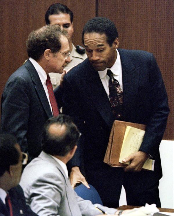 Defense attorney Alan Dershowitz discussing with OJ Simpson during a pretrial hearing, as lead attorney Robert Shapiro listens intently.