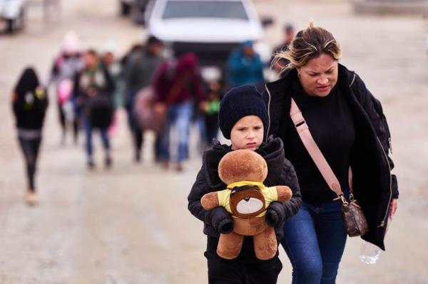 Migrants arrive to a makeshift camp after crossing into the US from Mexico