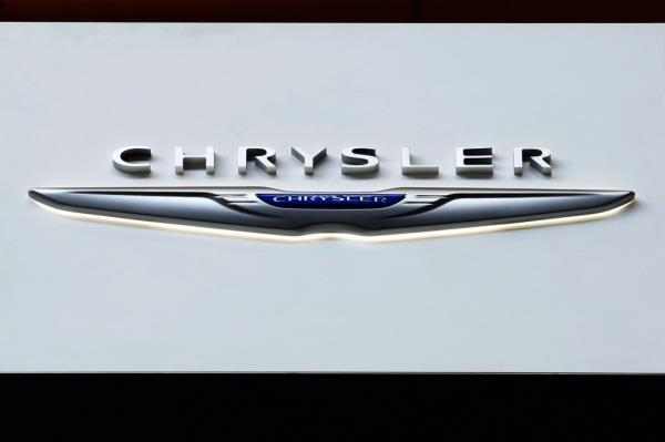 Chrysler logo on display at an auto show with a caption a<em></em>bout recalling over 211,000 SUVs and pickup trucks due to a software malfunction