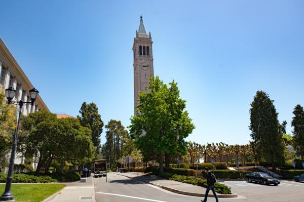 A young male student walks past Sather Tower 