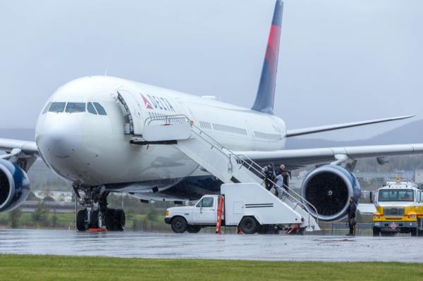 The unidentified suspect is seen being escorted off the Delta flight by police.