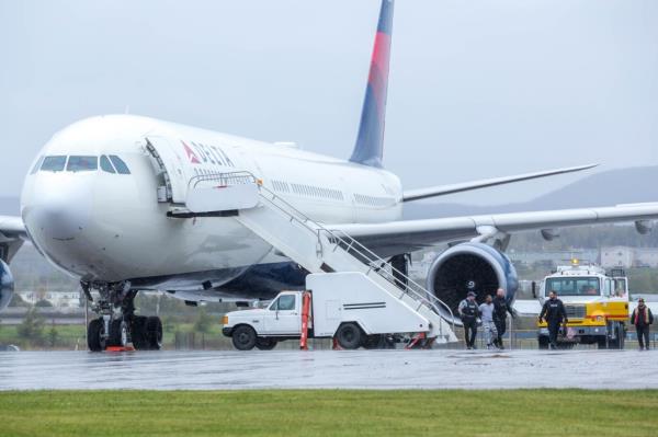 The unidentified suspect is seen being escorted off the Delta flight by police.