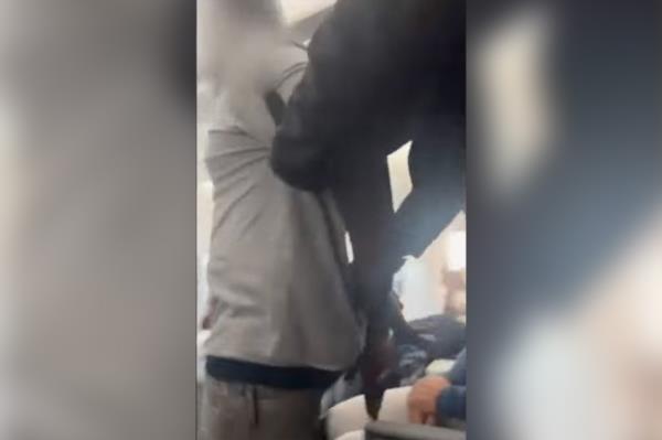 The alleged unruly passenger is seen in cuffs being taken down the aisle of the plane by police.