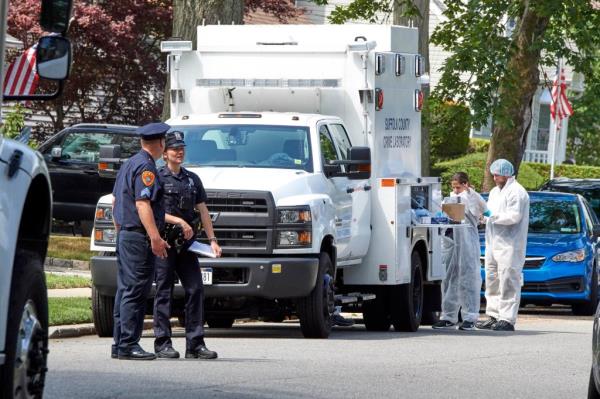 Suffolk County Police in uniform and suited up in crime scene gear outside of Rex Heuermann's home. 