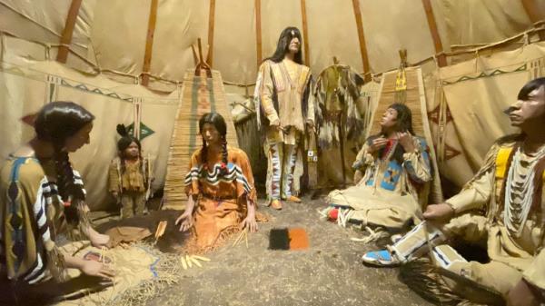 A museum diorama appearing to show Native American people inside a large circular tent structure