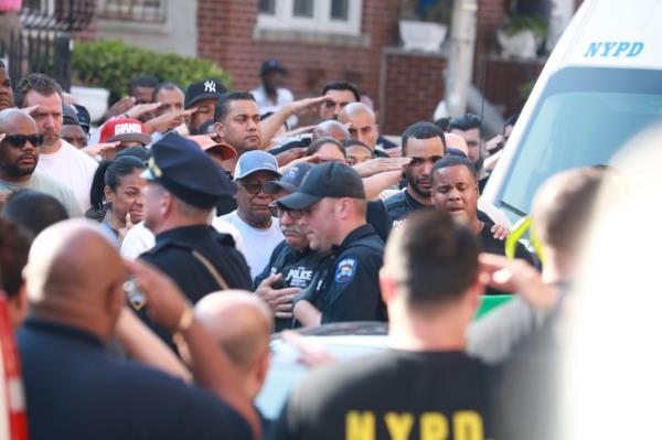 NYPD perso<em></em>nnel salute as the officer's body is removed from the house.