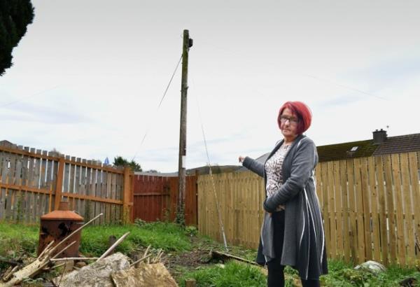 Ellen Ballantyne with the mast in her back garden. Photo release November 10 2023. See SWNS story SWLSmast. A pensio<em></em>ner has been hit with ?1,000 bill to have a telecom company's mast wires moved in her garden. Ellen Ballantyne, 67, wants to lay decking and have an outdoor seating area at her home. But broadband provider Openreach say she'll have to stump up to get it the way she wants. A mast and 'stay wire' have been prominent 'features' in resident Ellen's garden for more than 20 years.